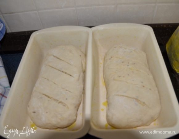 Разделите тесто на 2 части, сформируйте каждую в батон и уложите в смазанные маслом формы (у меня формы примерно 13*23). Сделать на каждом батоне 4-5 диагональных надрезов. Накрыть полотенцем и оставить расстаиваться на 1-1,5 ч. или до тех пор, пока буханки не увеличатся вдвое. 