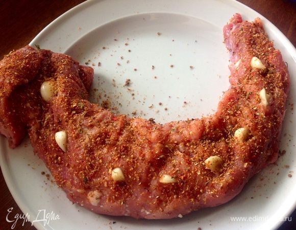 Промытое мясо отделим от пленок, хорошо промакнем бумажными полотенцем, делаем прорезы, начиним эти прорезы разрезанным на кусочки чесноком и хорошо обмажем солью и густо специями.