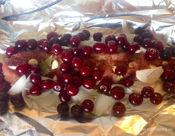 Выкладываем наше мясо на несколько листов фольги, чтобы не вытек сок, посыпаем помытой вишней, выкладываем порезанный лук и лавровый лист.