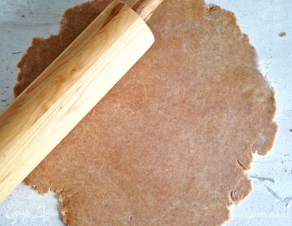 На слегка присыпанной мукой поверхности раскатываем тесто в круг, затем перекладываем его на коврик для выпечки или на пергамент.