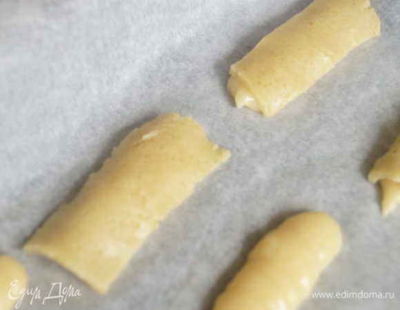 Теперь достанем наш кракелюр и нарежем полосками, размером с палочку из теста и накроем им наш будущий эклер. Выпекаем эклеры в разогретой до 200 гр духовке около 25-30 минут. Духовку во время выпечки, первые 15-20 минут не открываем, иначе эклеры осядут. В итоге кракелюрная корочка красиво "обнимет" эклер. Таким образом выпекаем эклеры, пока не закончится все тесто.
