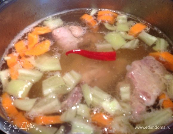 Бульон приправьте зирой и кориандром, посолите, добавьте стручок красного перца (через 10 минут его надо будет достать и выбросить), морковь, картофель и болгарский перец, и дальше варите на среднем огне. Через 20 минут добавьте помидоры и чеснок, и варите еще 5-7 минут.