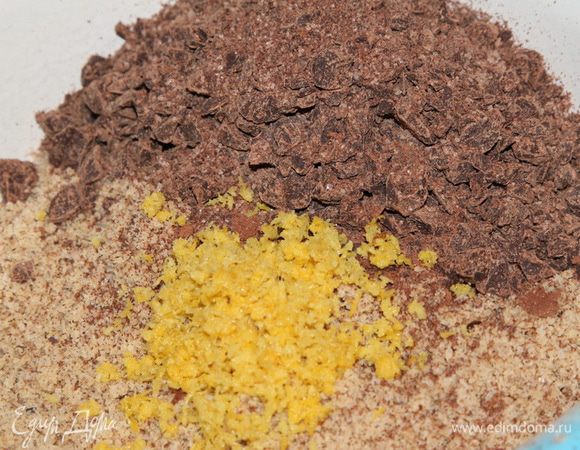 Поджаренные, остывшие и очищенные орехи переложить в чашу блендера и взбить с 1 столовой ложкой сахара до состояния мелкой манной крупы. Переложить в отдельную посуду. Крупно нарубить шоколад, переложить в блендер. Добавить 1 столовую ложку сахарного песка и на режиме «Пульсант» сделать несколько оборотов, измельчив шоколад до консистенции крупной крошки. Переложить шоколад в посуду с орехами, добавить тертую цедру, перемешать.