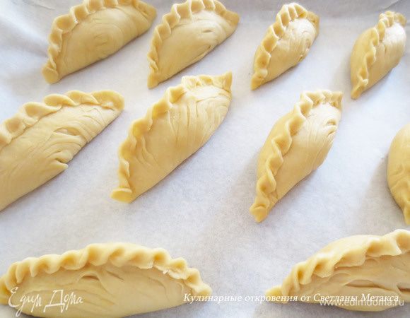 Противень застелить пергаментной бумагой и положить пирожки. Выпекать при температуре 200-210 градусов 40 минут. Затем вынуть пирожки, смазать их поверхность взбитым желтком и выпекать еще 10 минут при температуре 190 градусов.