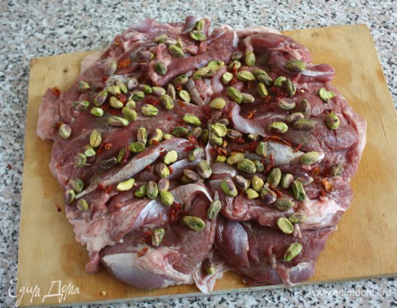 Положить чуть внахлёст 2 куска мяса кожей вниз.
Приправить солью, перцем, распределить равномерно крупные хлопья паприки и фисташки.