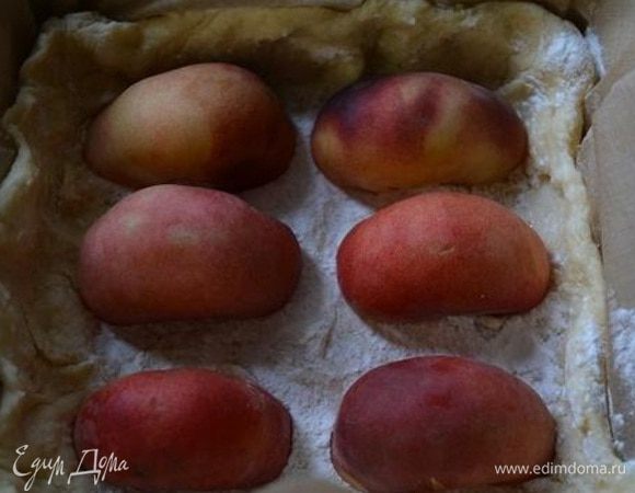 Форму с тестом достать из холодильника, присыпать крахмалом и уложить половинки персиков срезом вниз.