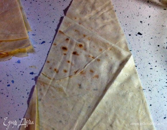 На основание треугольника (его короткую часть) положить немного начинки, примерно 0,5-1 чайной ложки. Слегка разровнять, оставляя свободными края по 2 см с каждой стороны. 