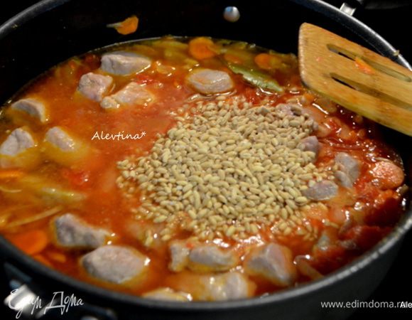 Добавим перловку, перемешаем, вернем свинину. Закроем крышкой и тушим 1 час.