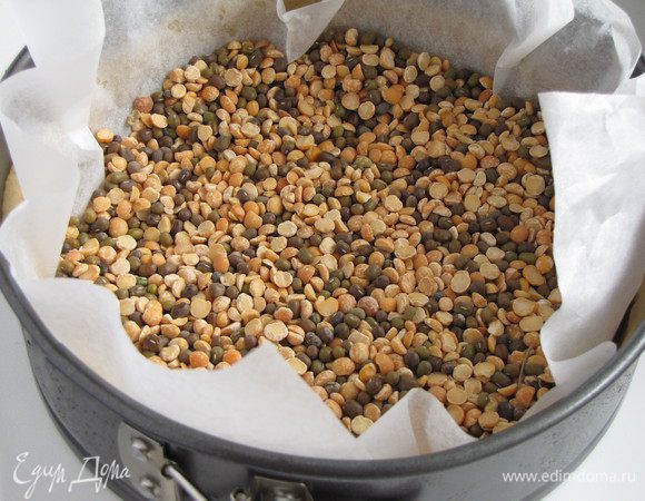 Накрыть тесто бумагой для выпечки и положить какой-нибудь груз. У меня смесь гороха и чечевицы, которую я постоянно использую для этих целей. Выпекать 15 минут при 190 град., затем убрать бумагу с фасолью и печь еще 5-7 минут.