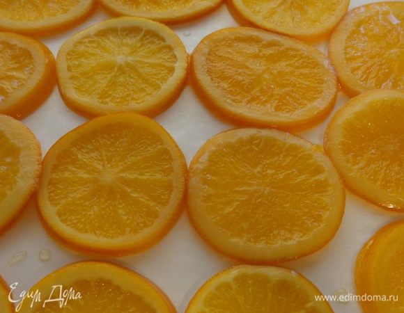 Апельсины выложить на противень, застеленный бумагой для выпечки и поместить в духовку минут на 30 при 100 градусах. Так они примут красивый карамельно-прозрачный вид.