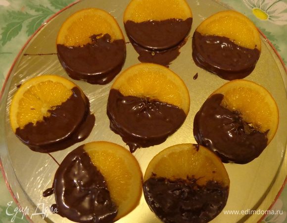Вынуть апельсины из духовки, дать им остыть. Блюдо застелить пищевой пленкой. Обмакивать до середины апельсиновые кружочки в шоколад и выкладывать на блюдо. Охладить в холодильнике до застывания шоколада.
