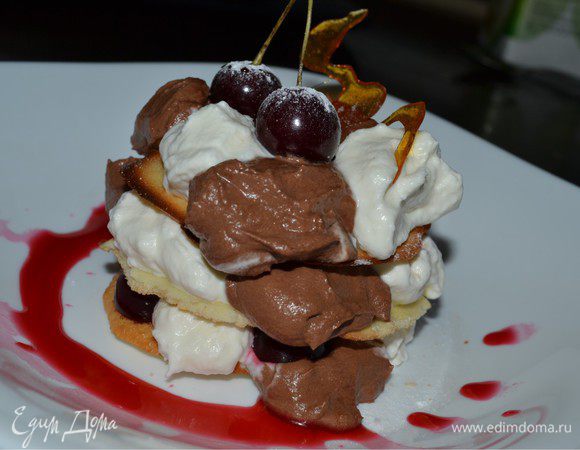 Начинаем собирать наш десерт. Выкладываем бисквит основу. На него с помощью ложки по очереди выкладываем крем с темным и белым шоколадом. Затем добавляем свежую вишню разрезанную пополам, без косточки. Накрываем еще одним пластом и все повторяем. Можно сделать не 3 слоя а больше. Как вам нравится. Сверху десерт украшаем карамелью и ягодами вишни. Подаем с вишневым топпингом. Приятного аппетита!