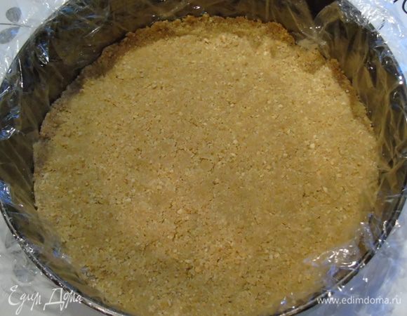 Форму выложите пленкой (диаметр 23 см). Масло растопите с смешайте с печеньем. Выложите в форму и утрамбуйте. Отправьте в холодильник.