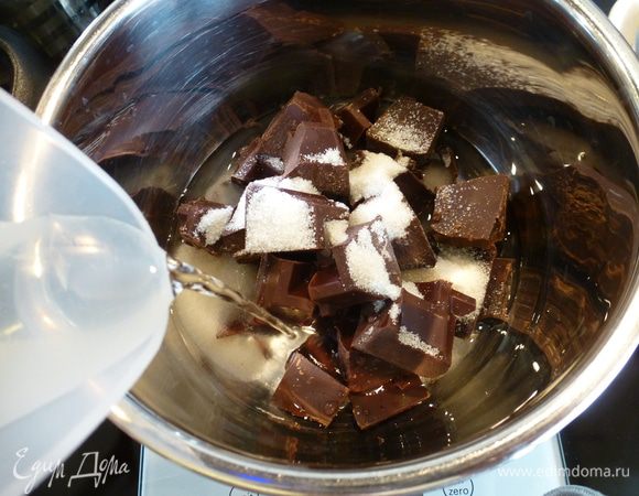 Только теперь переходим к приготовлению шоколадного мусса. Заранее готовить его не нужно! Смысл приготовления заключается в том, чтобы шоколадную массу сначала нагреть, а потом при резком охлаждении взбить ее до нужной консистенции.
Итак, для мусса в сотейник выкладываем кусочки шоколада, сахар, коньяк (или другой крепкий напиток для вкуса) и наливаем воду.
