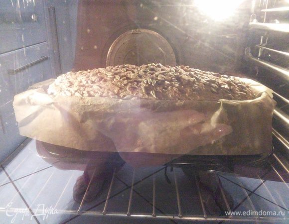 Смочить хлеб водой и поставить в холодную духовку на решётку. Включить на 180°С и выпекать 90 минут. Если верхушка начнёт сильно запекаться, накройте хлеб листом пергаментной бумаги. 