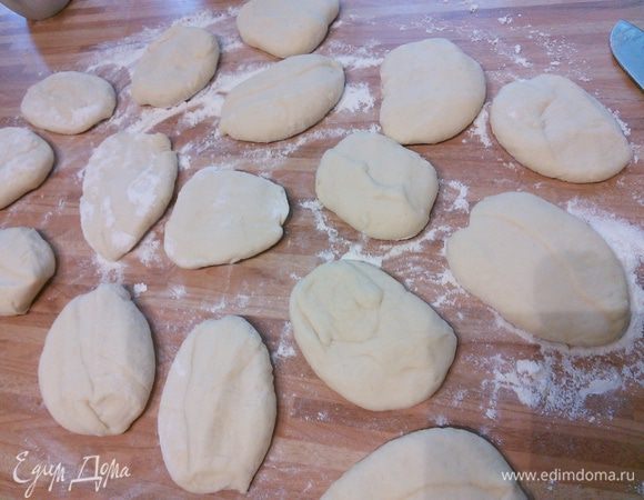 На посыпанной мукой поверхности разделите тесто на порции по 50 г, их получится 16 штук. Слегка приплюсните заготовки рукой.