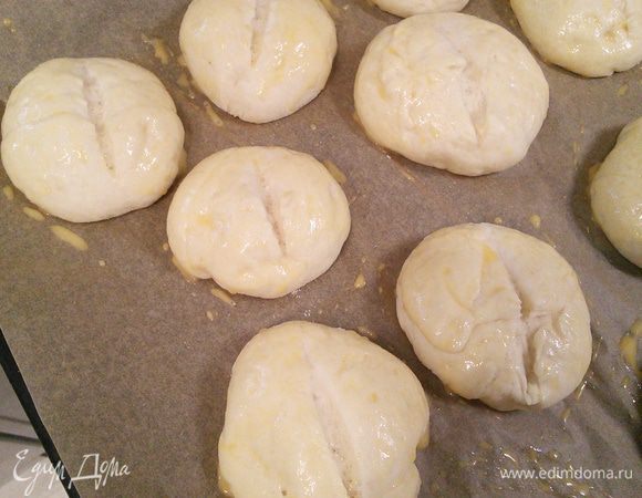 Духовку разогрейте до 200°С. Желток соедините с оставшимся молоком, смажьте кисточкой булочки по бокам, оставляя не смазанным разрез.