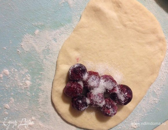 Каждый кусочек раскатать овальной формы. На верхний край положить вишню, посыпать сахаром.