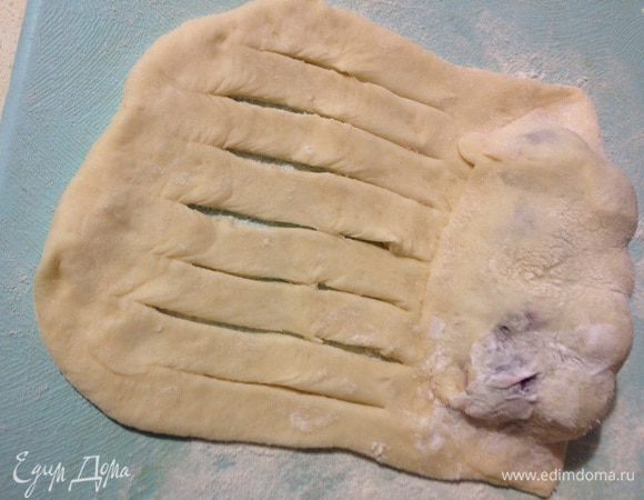 Накрыть верхним краем теста, края придавить чтобы начинка не вытекла. Оставшийся край порезать на полосочки, не дорезая до конца. 