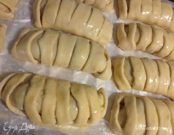 Свернуть булочку, выкладывать на противень, чтоб край оказался снизу. Повторить со всеми булочками. Смазать булочки взбитым яйцом. Выпекать 20 минут при температуре 180 градусов. 