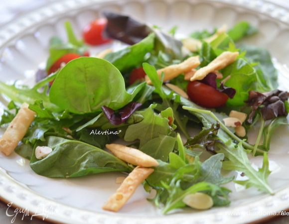 Салат разложить по тарелкам. Помидоры черри на 2 части разрезать. разложить. Посыпать миндальными пластинками по желанию, чипсами или подсушенной питой, поломанной на кусочки.