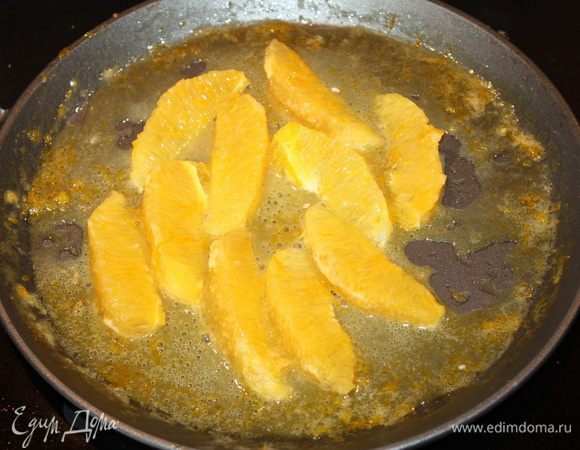 Апельсиновые дольки опускаем в соус, даем им хорошо прогреться, а затем выкладываем на блины.