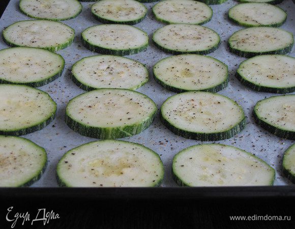 Цукини нарезать кружками толщиной 0,5 см выложить на противень застеленный пекарской бумагой (бумагу с помощью кулинарной кисти смазать маслом). Посолить и поперчить, каждый кружок смазать оливковым маслом. Поставить в духовку на 180 гр и запекать до зарумянивания минут 15-20.