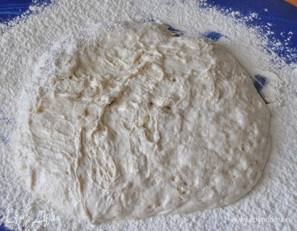 Через положенное время, стол густо присыпать мукой. Тесто очень липкое, муки не жалеть. Слегка соскребая силиконовой лопаткой тесто со стенок, выложить его на стол. Тесто не обминать, стараясь максимально сохранить образовавшиеся пузыри!