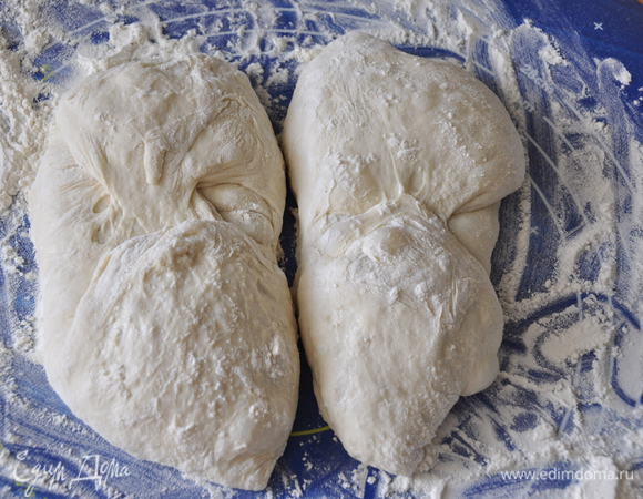 В месте, где нет сквозняков, подготовьте льняное или вафельное кухонное полотенце. Чем лучше выражен рисунок на ткани, тем лучше. В идеале, этот рисунок отпечатается на хлебе и придаст поверхности характерный узор.  Равномерно и густо присыпьте ткань мукой. Обращаю внимание, что надо хорошо присыпать мукой, чтобы тесто впоследствии не приклеилось. Это важно! 
Разделите тесто на две части – разделите силиконовой лопаткой и раздвиньте в стороны.