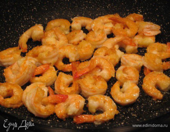 Креветки очистить, удалить пищевод, помыть, выложить на бумажные полотенца, обсушить. 
В сковороде разогреть 1 ст. л. оливкового масла, слегка обжарить раздавленную очищенную дольку чеснока, чеснок выкинуть. 
Креветки обвалять в манке, обжарить на среднем огне до румяного цвета.