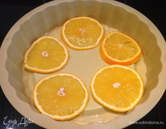 Один апельсин нарежьте кружочками и выложите на дно формы. Второй апельсин очистите и нарежьте небольшими ломтиками.
