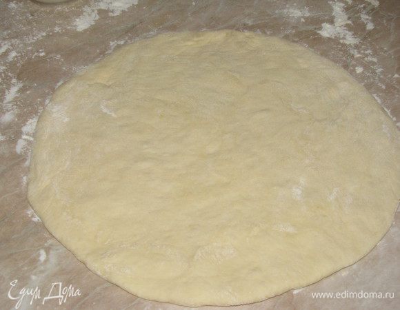 Ладонью размять тесто в лепешку толщиной 7-10 мм (не забыть подпылить стол мукой).