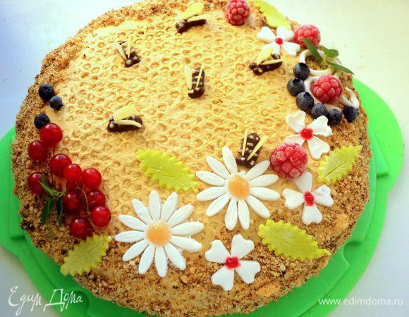 Снять пленку с верха торта и украсить цветочками из мастики, ягодами и шоколадными пчелками.