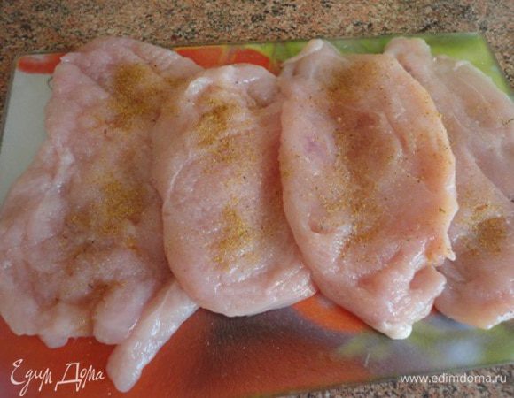 Куриные грудки разрезать вдоль пополам, завернуть в пищевую пленку и отбить. Затем натереть солью и специями.