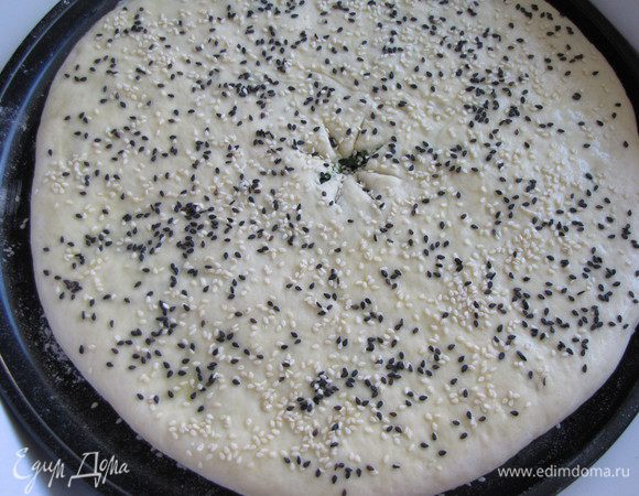 Разровнять поверхность пирога, разминая его так, чтобы получилась круглая лепешка. Перевернуть на другую сторону, аккуратно выложить на противень (я выложила в специальную форму для пиццы, немного присыпав ее мукой). В середине сделать в тесте надрез для выхода пара. Выпекать в разогретой до 200С духовке 15-20 минут.