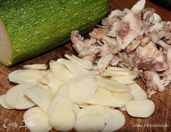Чеснок чистим, нарезаем на тонкие пластинки, приготовленное куриное мясо тоже нарезаем кусочками, от цукини отрезаем половину.