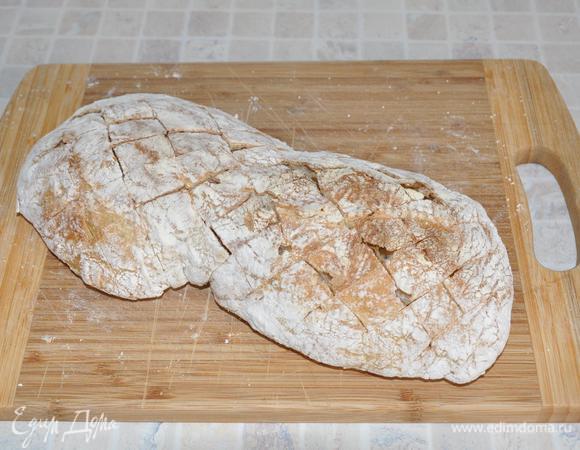 Острым ножом сделать на хлебе Х-образные разрезы, не прорезая низ хлеба.  Уложить хлеб на фольгу. 
