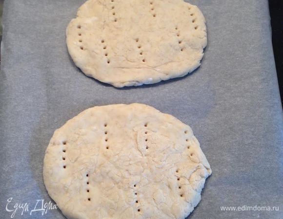 Когда тесто увеличилось разделить его на 6 равных частей. Из каждой части сформировать достаточно толстые лепешки, переложить их на пергамент и наколоть вилкой.