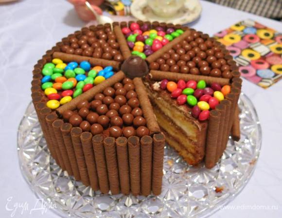 Переходим к декору.
Высота торта должна не превышать длину вафельных трубочек. Идеально - трубочки выше на 1 см, чтобы "частокол" из них выполнял функцию бортиков для шоколадных шариков. У меня трубочки оказались чуть выше в горизонтальном виде, пришлось на 0,5 см подрезать каждую. Ставим "трубочный заборчик". Фиксируем его вокруг красивой соломкой)

Верх торта делим трубочками на  шесть секторов. В центр – ставим любимую конфетку именинника.

Аккуратно выкладываем весь набор шоколадных шариков (с орешками, изюмом и воздушным рисом внутри), цветных шоколадных драже, цветных драже с застывшим соком внутри. Сектора чередуем – шоколадные и цветные. Ставим свечки, зажигаем, вносим в зал!

Гости были в восторге! Именинник – счастлив и горд за маму! 
Через день пришлось повторить – уже для подростковой вечеринки в ресторанчике. Эффект – тот же, плюс "Ого!" от шеф-повара ресторана ;)

Всем – наслаждения!   