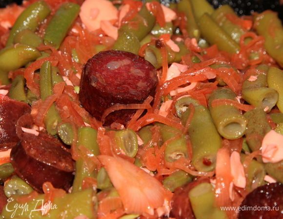 Отварную фасоль отбрасываем на дуршлаг, обдаем холодной водой, даем стечь и отправляем к колбаскам. Добавляем водички и тушим 10 минут, помешивая периодически.