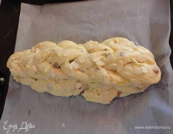 Уложите третью косичку. Оставьте расстаиваться на минут 30. Затем смажьте белком и посыпьте миндальными лепестками.