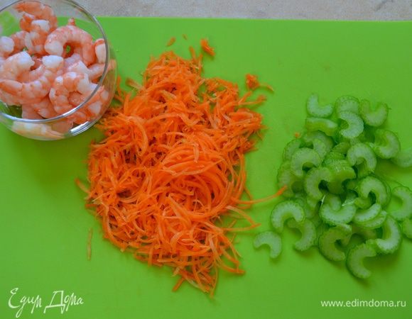 Подготовьте креветки и овощи. Креветки отварите 2 минуты в кипящей воде вместе лавровым листом и несколькими горошинками чёрного перца. Очистите хвостики готовых креветок. Крупную морковь (или две средних) очистите и нарежьте жульеном (тонкими полосочками). Стебель сельдерея нарежьте тонкими пластинами.
