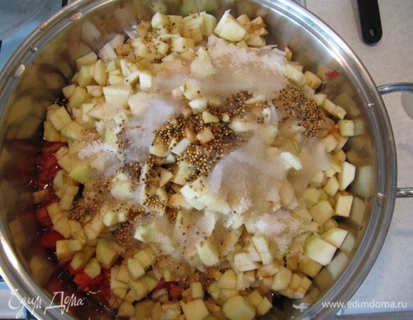 Лук измельчить. Яблоки очистить от кожицы, удалить сердцевины и мелко нарезать. 
В кастрюлю с толстым дном (у меня 5-литровая) положить нарезанные помидоры, лук и яблоки. Добавить зерна горчицы, сахар и яблочный уксус. Поставить на несильный огонь и варить, периодически помешивая, 2 часа. Время варки может несколько отличаться. Как только консистенция станет достаточно густой, разложить чатни в стерилизованные банки и закрыть стерилизованными крышками. Укутать полотенцами и оставить остывать.