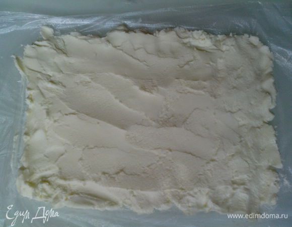 На пищевую пленку выложить сыр Маскарпоне и распределить равномерно, придать форму прямоугольника.
