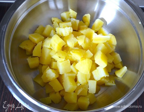 Картофель очистить от кожуры и нарезать небольшими кубиками. Выложить в большую миску-салатник.