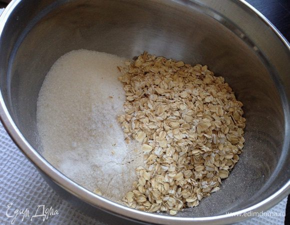 В миску просеять муку с разрыхлителем. Добавить соль, сахар, овсяные хлопья. Перемешать.