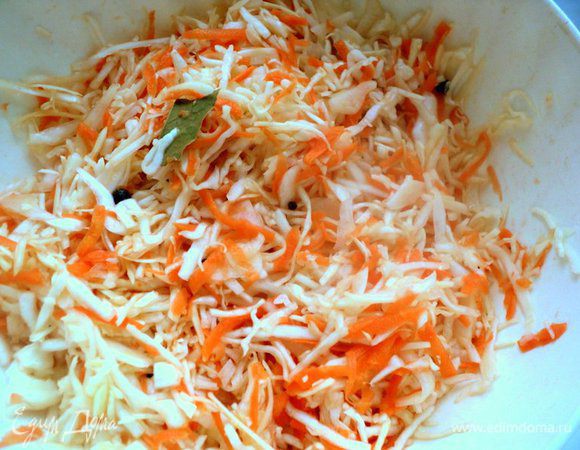Капусту необходимо брать белокочанную круглой формы, ни в коем случае не приплюснутую, сорта «Амагерка», она не такая сочная. Морковь натереть на терке.
Капусту тонко нашинковать  ножом или на специальной терке. Добавить к капусте морковь, соль, сахар и хорошо перетереть руками, чтобы капуста пустила сок.
Затем добавить черный и душистый перец, лавровый лист и перемешать.
