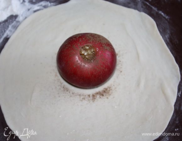 Раскатываем одну часть теста в форме круга и смазываем его слегка взбитым яйцом. Ставим яблоко в центр и заполняем его медово-ореховой начинкой. Сверху присыпаем корицей.