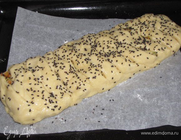 Перенести пирог на противень, застеленный пекарской бумагой. Смазать слегка взбитым яйцом и посыпать кунжутом. Поставить в духовку на 180С примерно на полчаса или до зарумянивания.