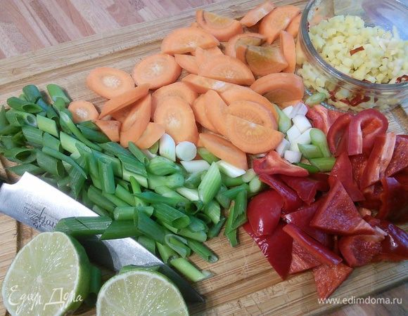Рис отварить в подсоленной воде, следуйте инструкции на упаковке. Морковь нарежьте кружочками, перец кусочками, зелёный лук наискосок брусочками. Мелко порубите имбирь (понадобится кусочек с грецкий орех), чеснок и чили (предварительно вынув семена). 